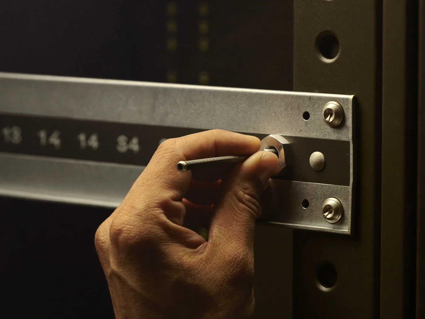 Hand setzt mit einem Werkzeug eine Käfigmutter in eine Rack-Schiene ein